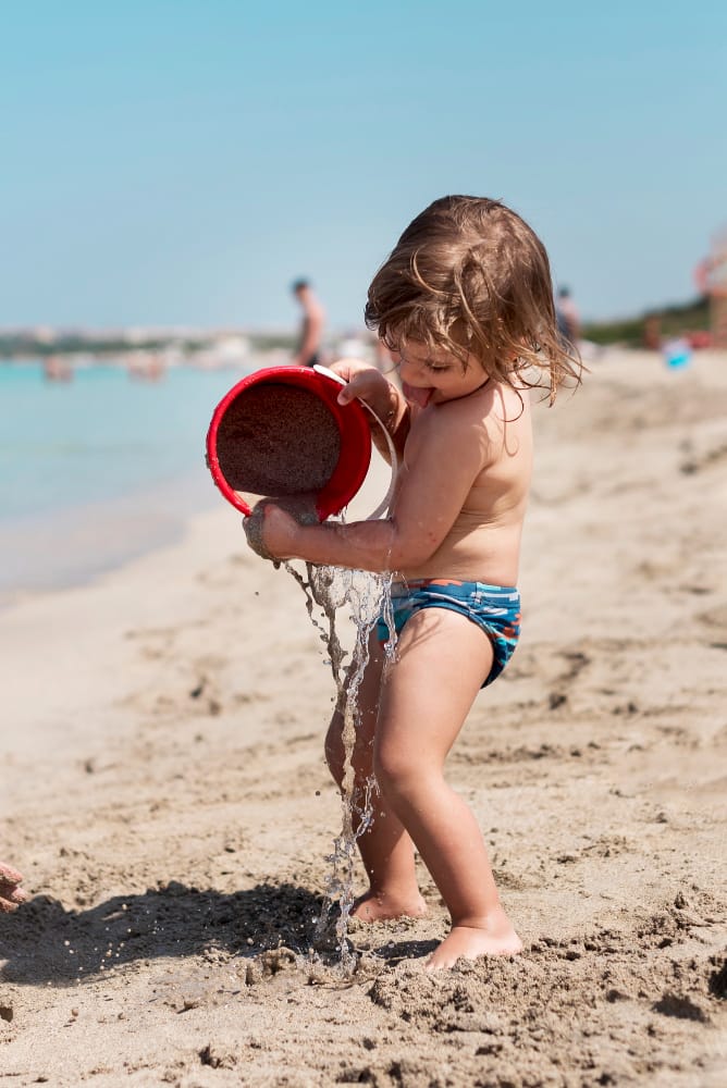 Niño jugando con la arena y agua en la playa de Isla Saona